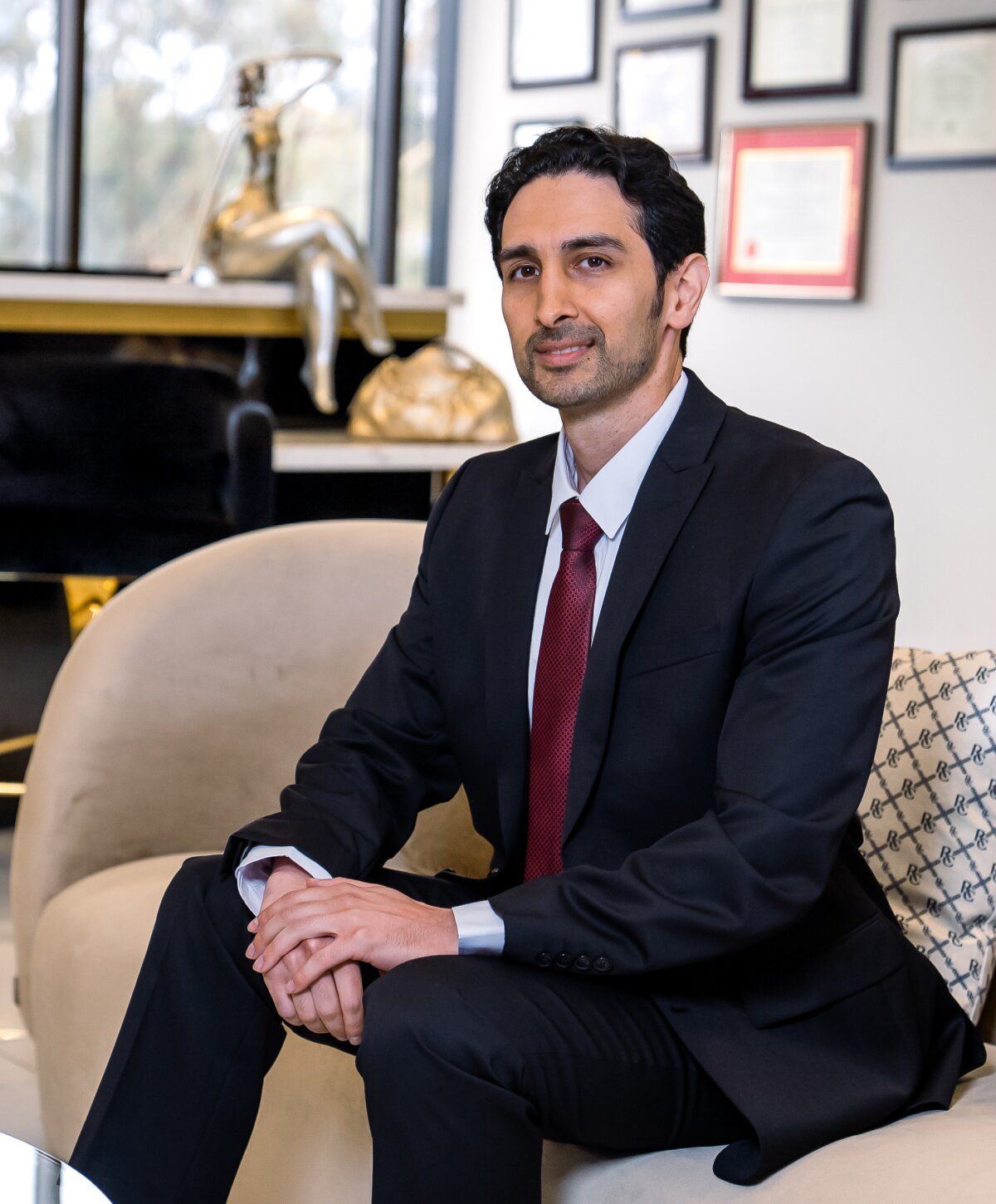 Dr. Ali Razfar in suit seated elegantly at the practice waiting room